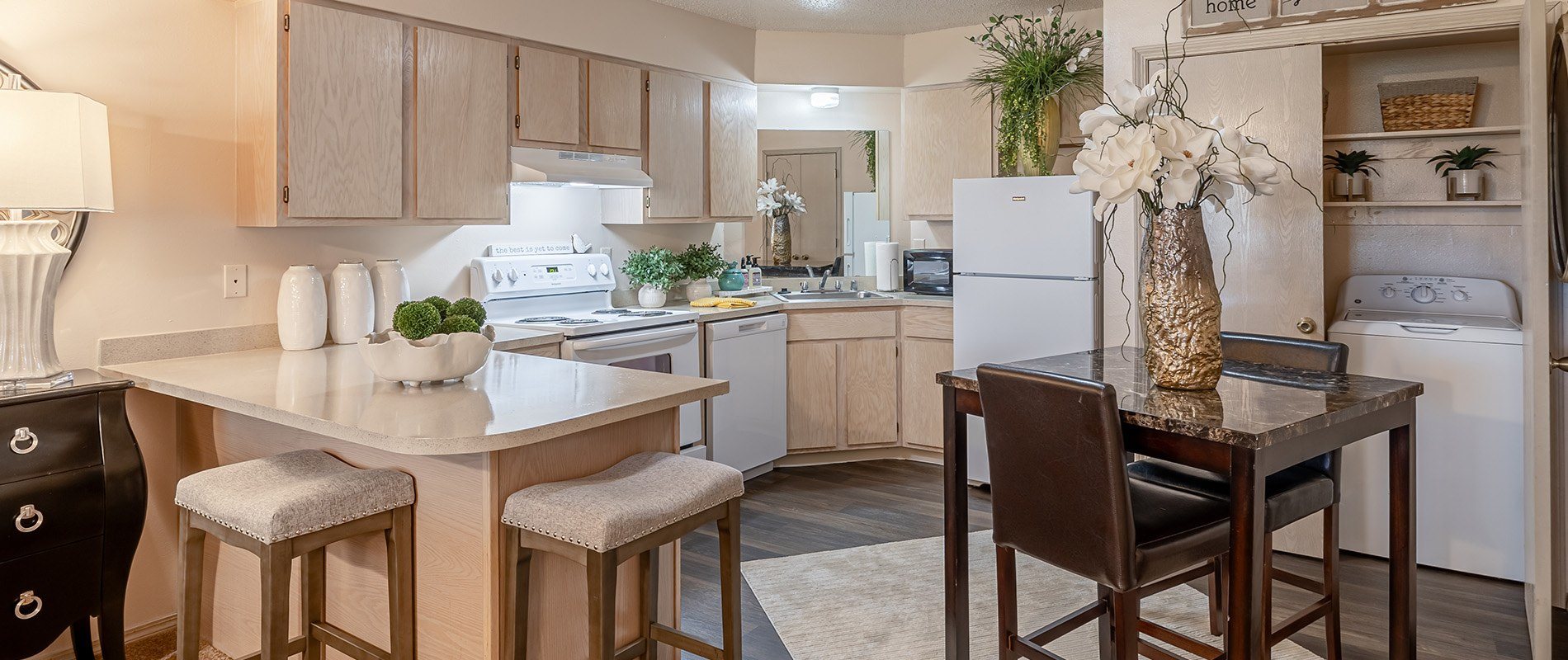 A kitchen with a table and chairs in the foreground and a refrigerator in the background.
